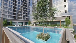 Un hôtel moderne doté d’une piscine sur le toit, entouré de verdure et avec un grand bâtiment en arrière-plan.