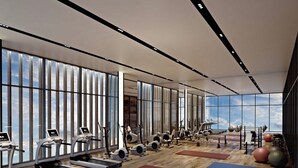 Une salle de sport moderne équipée de tapis de course, de vélos d’appartement et de divers appareils d’exercice.