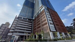 Un immeuble moderne de grande hauteur, doté d’une façade en verre et d’un mélange de styles architecturaux, dont une partie présente une façade extérieure en bois.