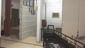 A spacious living area with a patterned wall, a staircase, and a bench. - Hotel O Guest House Bu Iin Syariah (Surabaya)