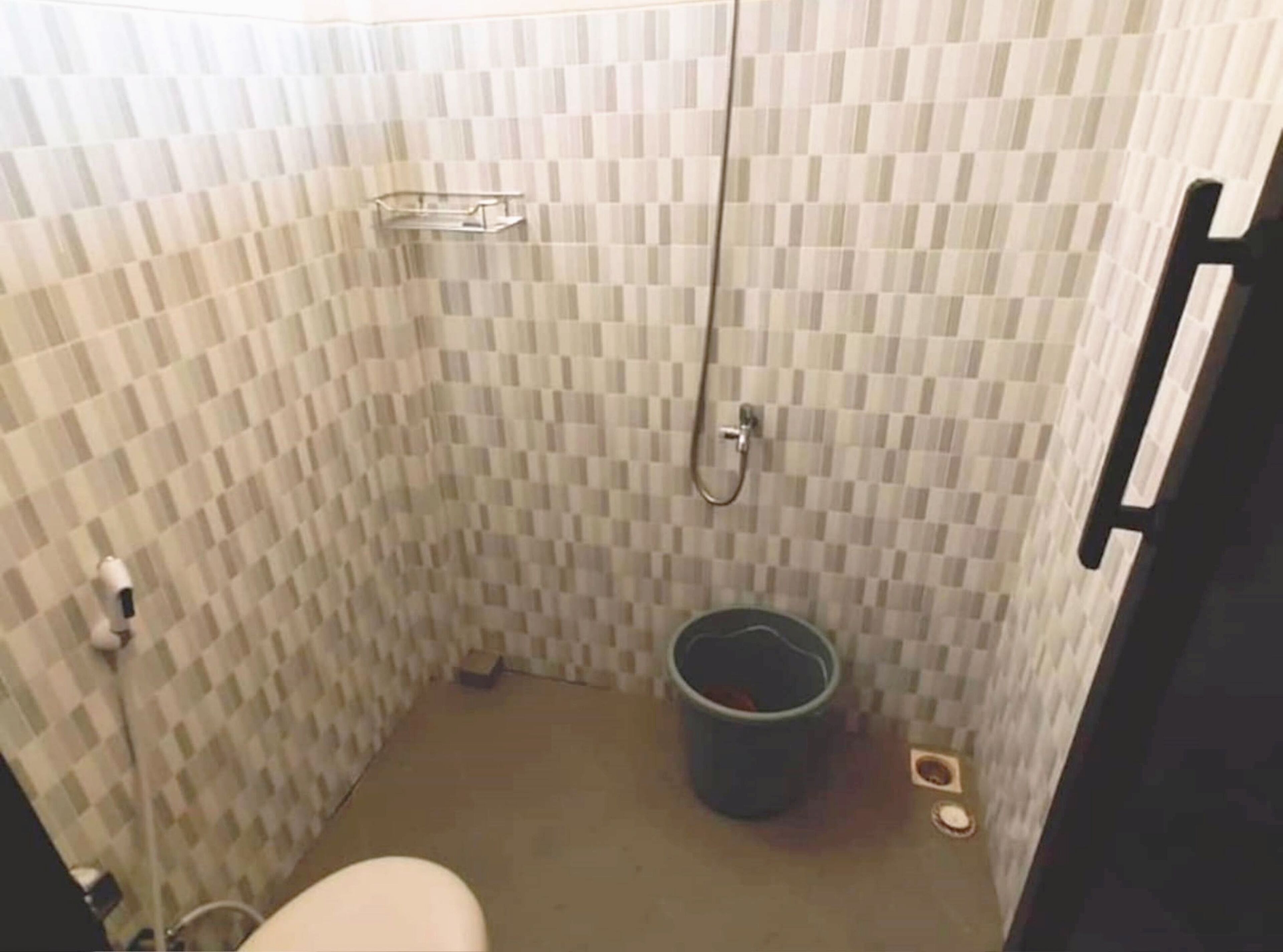 Ein kleines Badezimmer mit Toilette, Dusche und Mülleimer.