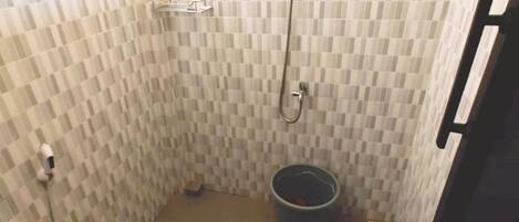Ein kleines Badezimmer mit Toilette, Dusche und Mülleimer.