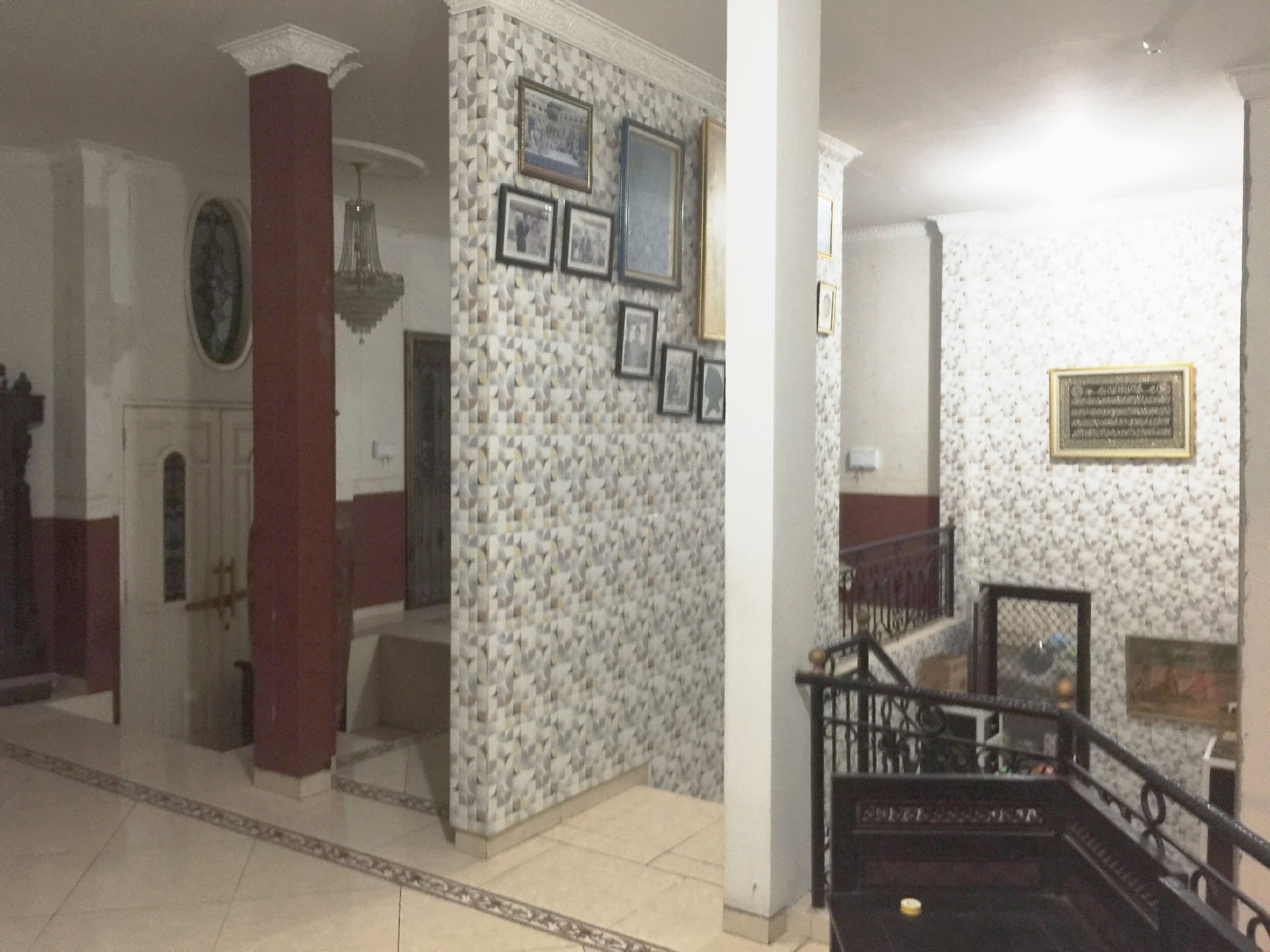 Un pasillo con papel tapiz estampado, una escalera y un cuadro en la pared.