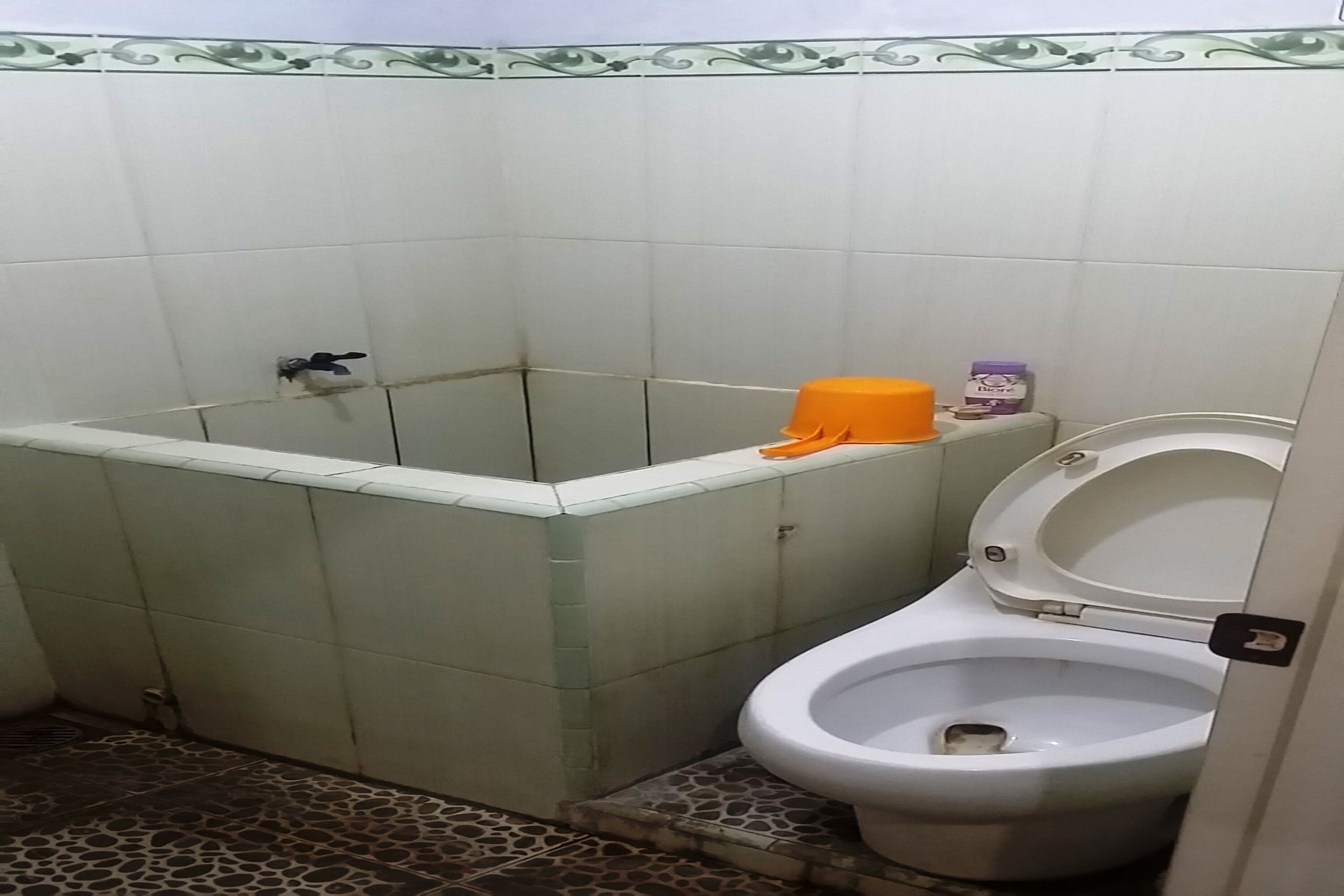 A bathroom with a shower, toilet, and a small shelf with toiletries.
