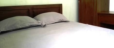 A bed with a wooden headboard and two pillows.