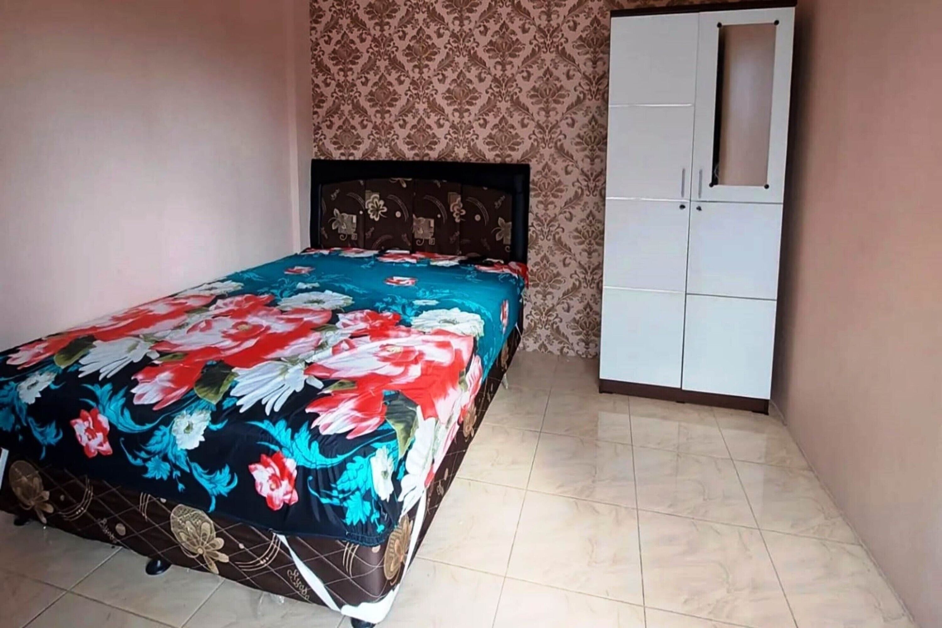 A bedroom with a bed, a wardrobe, and patterned wallpaper.