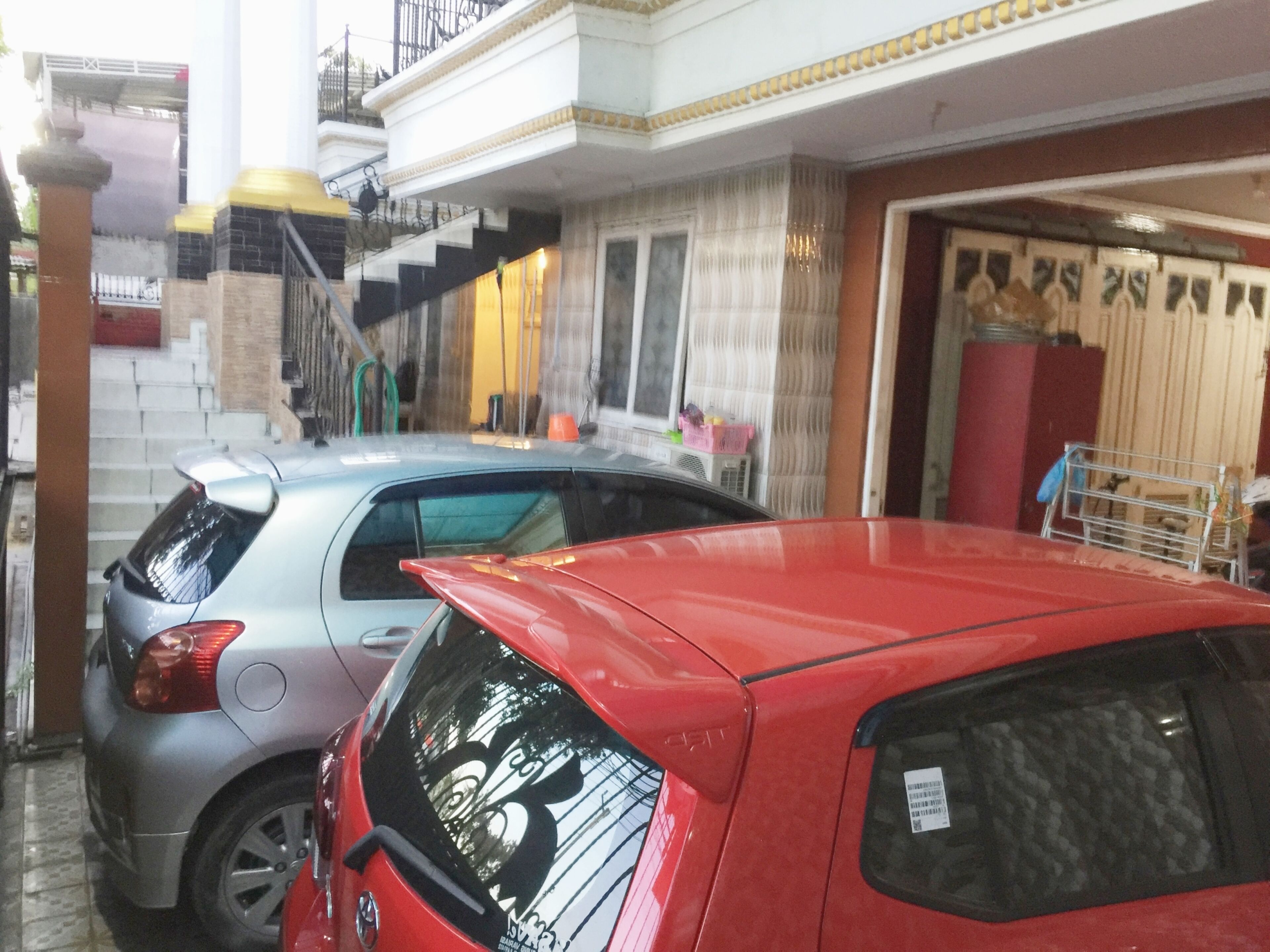 A parking area with two cars, a staircase, and a building entrance.