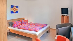 Een slaapkamer met een bed, een televisie op een meubel en een houten hoofdbord.