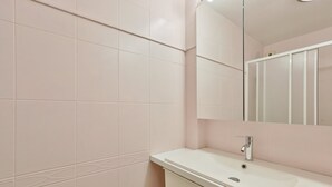 A bathroom with white tiles, a sink, a mirror, and a faucet. - Cosy Appart Avec Balcon à Proximité de la Villette (Paris)