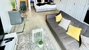 A modern living room with a grey sofa, a coffee table, and a bed with black and white bedding. - Stunning Studio Apartment in Cambridge (Cambridge)