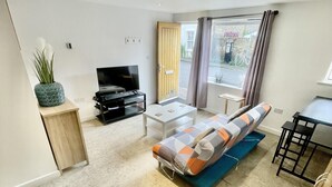 A modern living room with a sofa, a television, and a small table. - Beautiful Studio in Cambridge City Centre (Cambridge)