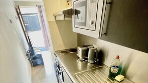 A narrow kitchen with a microwave, toaster, kettle, and sink. - Beautiful Studio in Cambridge City Centre (Cambridge)