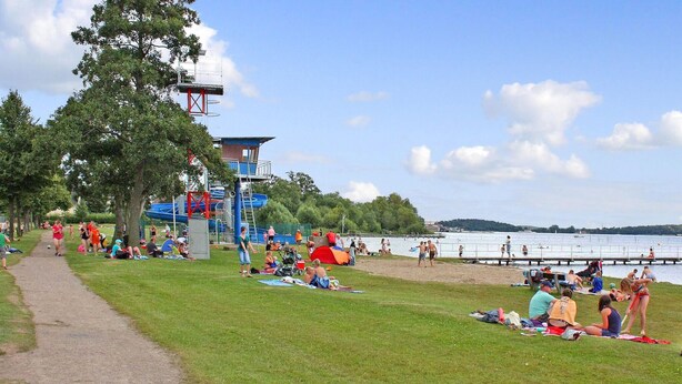 A park with a playground, a lifeguard tower, and a body of water. - Ferienhaus Waren (Müritz) (Waren (Müritz) OT Ware)