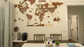 A dining area with a world map wall art, a coffee bar, and a table with chairs.