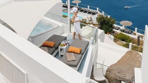 A rooftop terrace with a pool, lounge chairs, and a view of the sea. - Nevma Suites (Santorini)