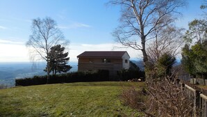 A house with a sloped roof, surrounded by a grassy yard and trees. - Studio on Monte Generoso (Castel San Pietro)