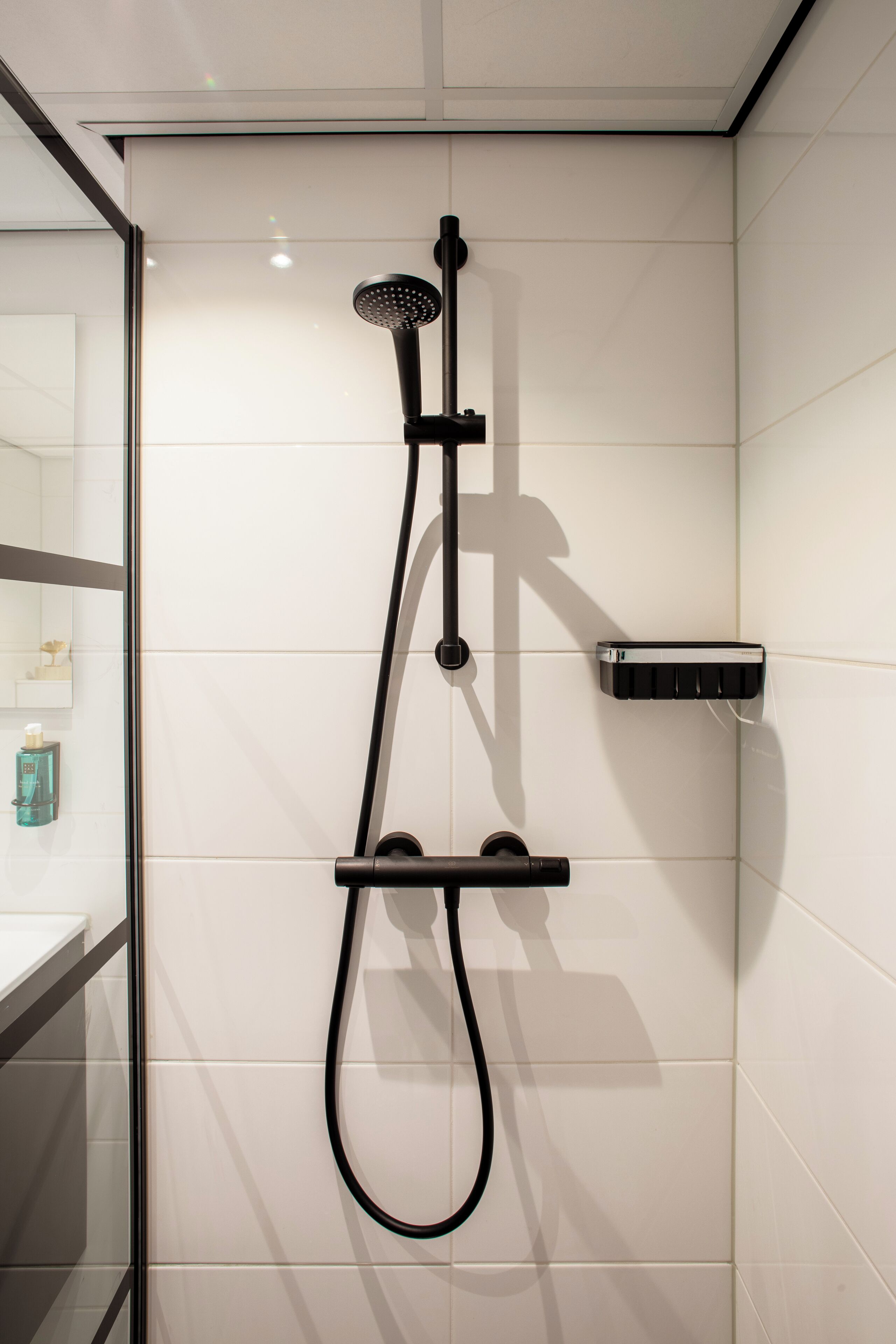 Une douche moderne dotée d’un pommeau de douche à main et d’un panneau de commande fixé au mur.