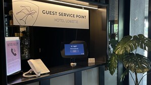 Asiakaspalvelupiste, jossa on digitaalinen näyttö, puhelin ja kyltti, jossa on hotellin nimi.