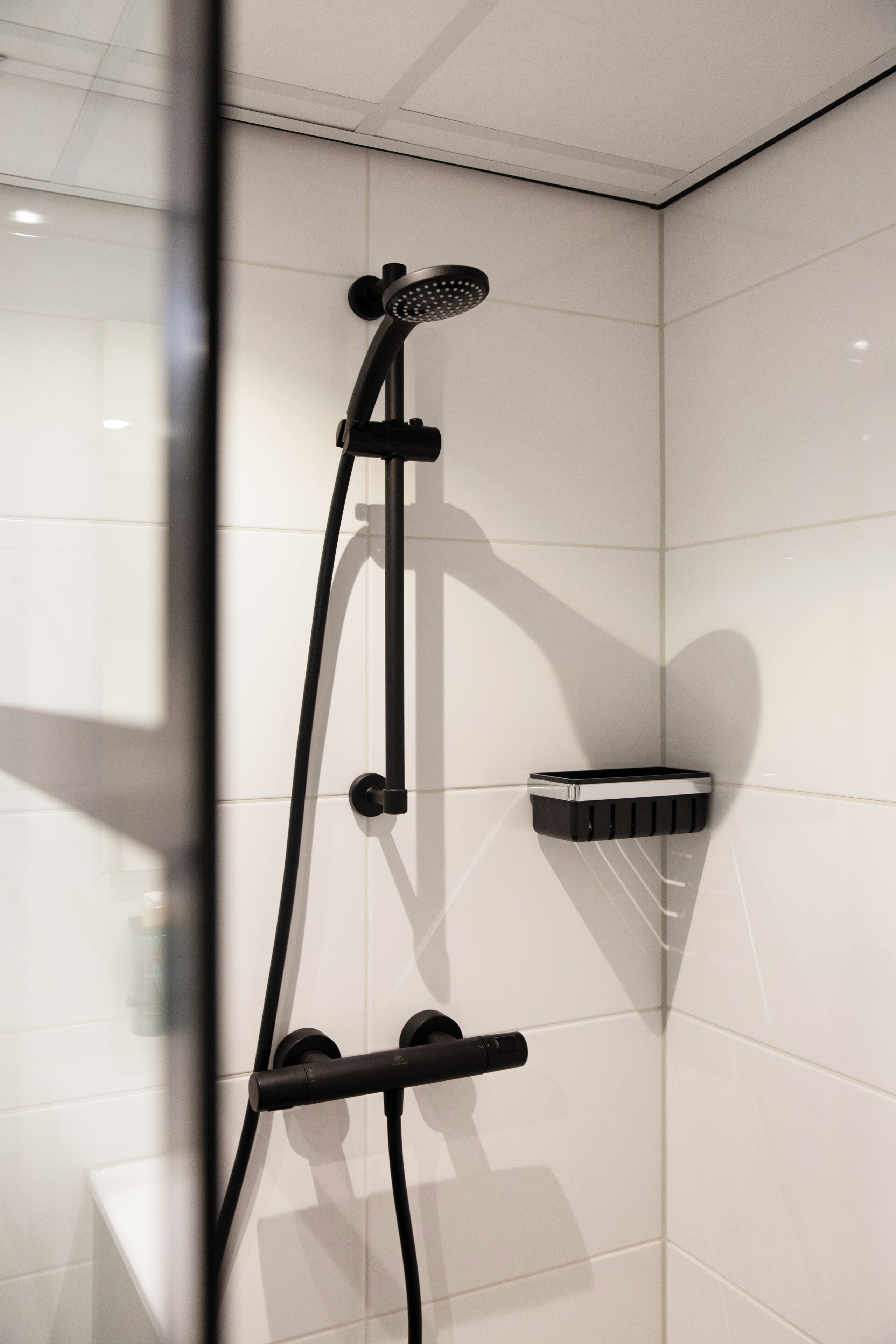 A modern shower with a handheld showerhead and a wall-mounted control panel.