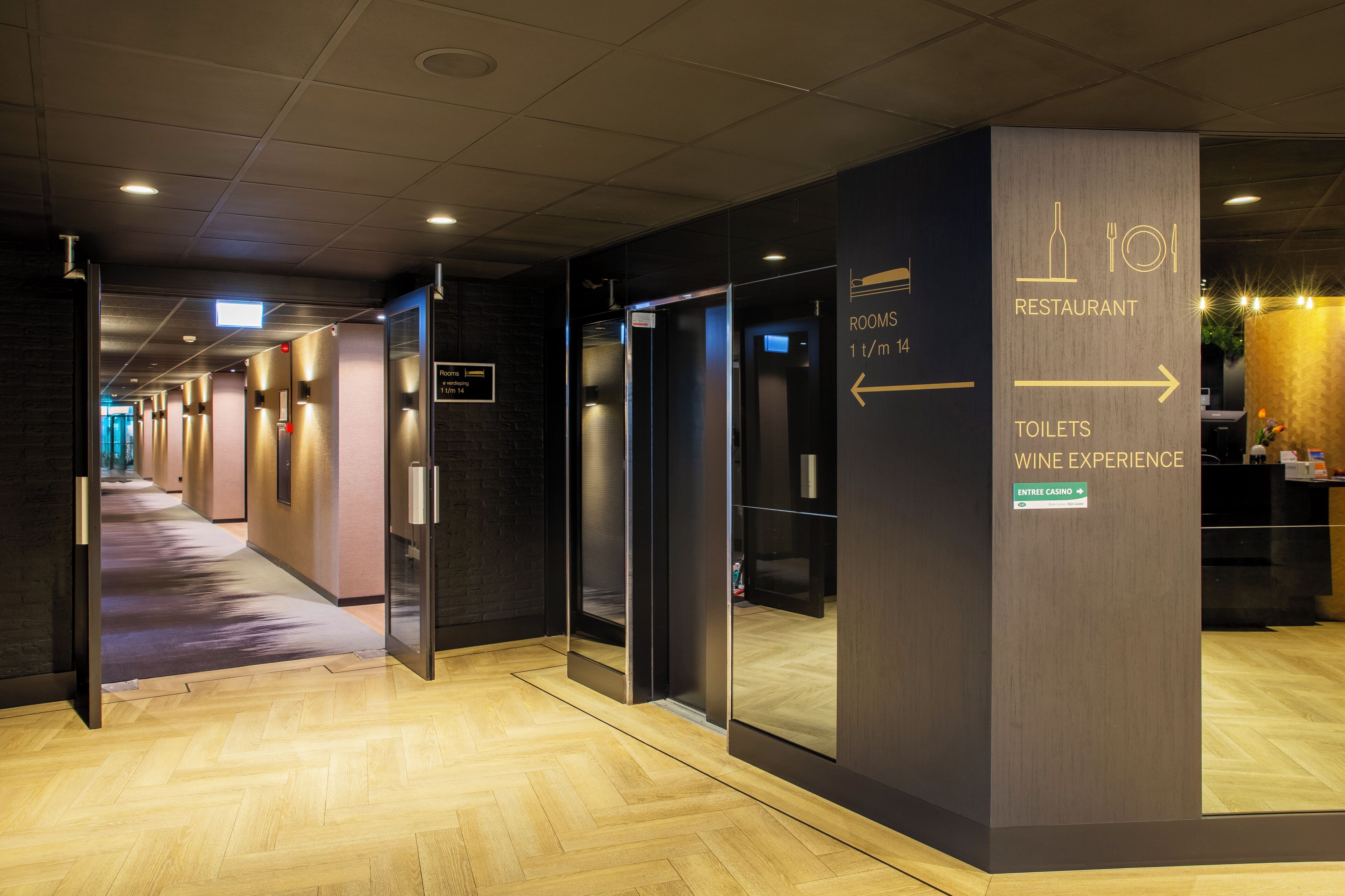 A hotel corridor with directional signs to the restaurant, toilets, and wine experience.
