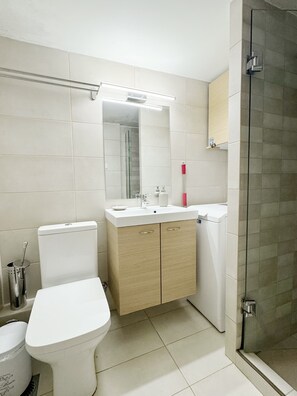 A modern bathroom with a toilet, sink, and shower. - John ,Home (Glifada)