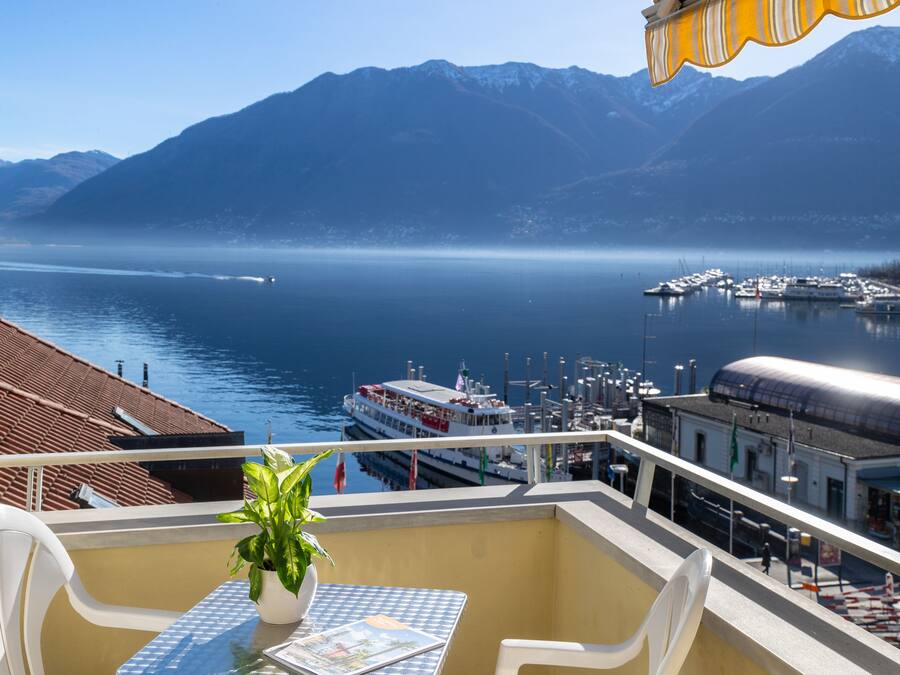 A balcony with a table, chairs, and a potted plant.