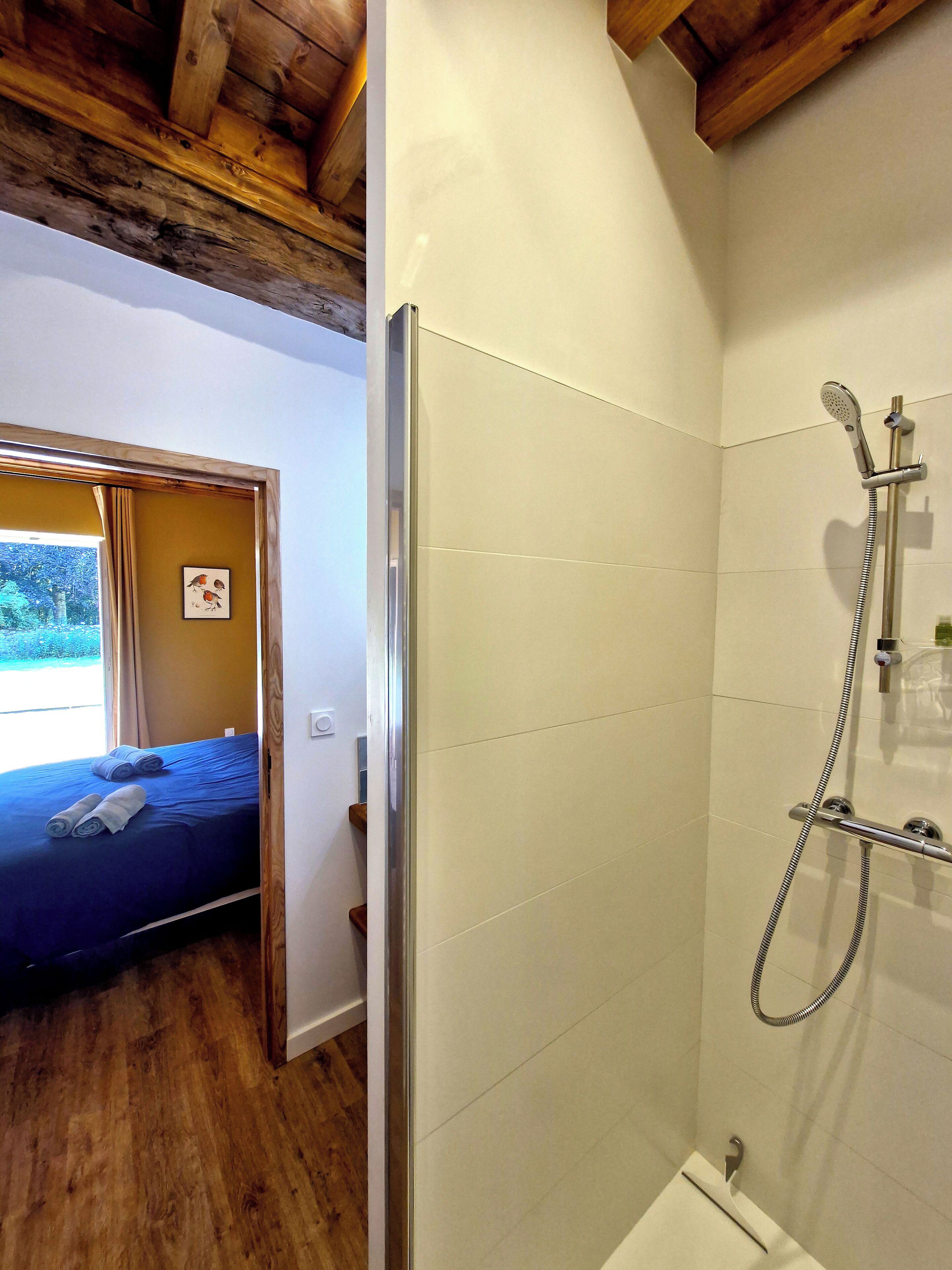 Una habitación con cama, ducha y ventana con cortinas.