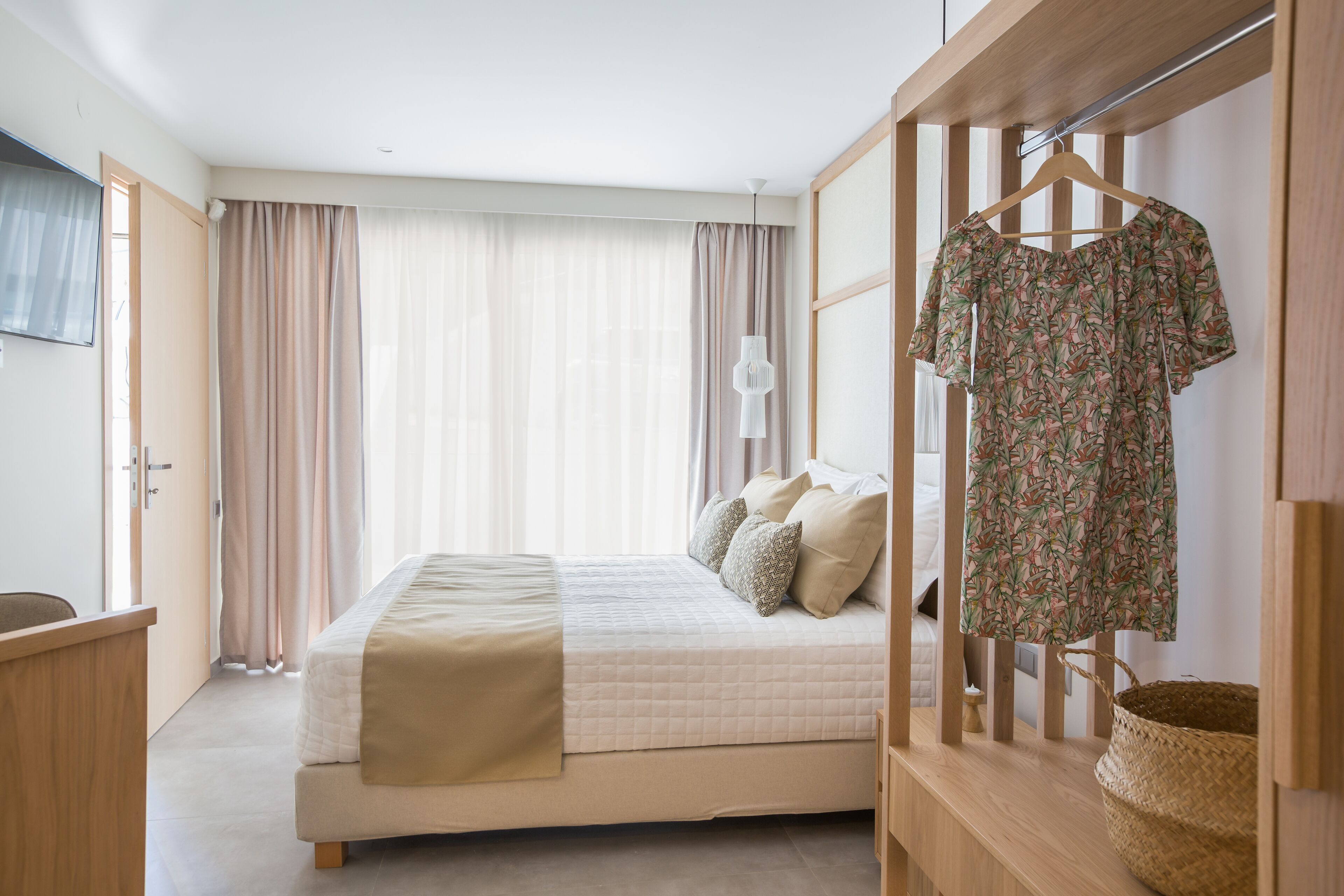 A bedroom with a bed, a desk, a wardrobe, and a hanging light fixture.