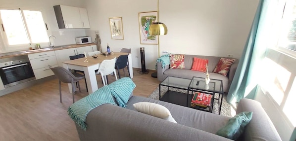Relax in this inviting living space with a cozy sofa, glass coffee table, and dining area.