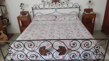 A bed with a floral bedspread, two bedside tables with lamps, and a guitar in the corner.