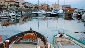 Un puerto deportivo con barcos amarrados, edificios al fondo y una superficie de agua tranquila.