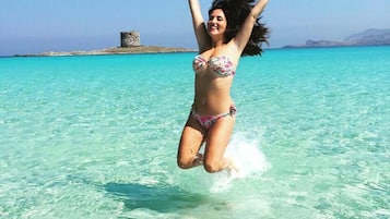 A person jumping into clear turquoise water with a castle-like structure in the background.