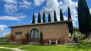 A small brick building with a tiled roof, a large arched doorway, and a bench in front.