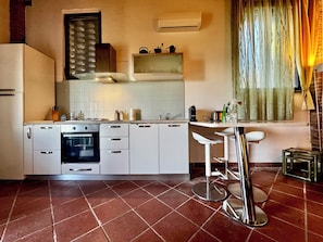 Una cucina con mobili bianchi, un fornello, un lavandino e un'area bar con sgabelli.