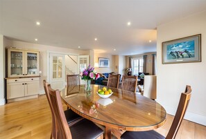 A dining area with a glass-top table, wooden chairs, and a bowl of fruit. - Spacious Home to Sleep 6 Just a Short Stroll From Kenmare (Kenmare)