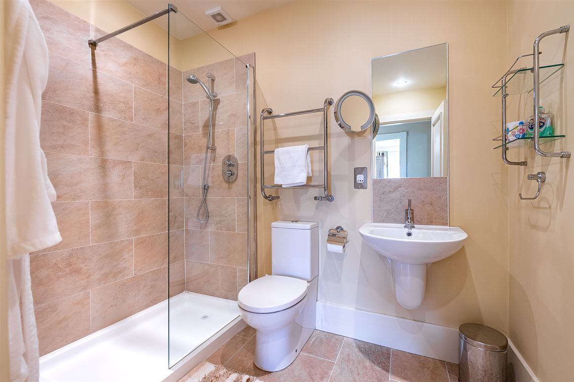 A modern bathroom with a glass-enclosed shower, a toilet, a sink, and a mirror.
