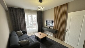 A modern living room with a sofa, a coffee table, a TV mounted on the wall, and a door.
