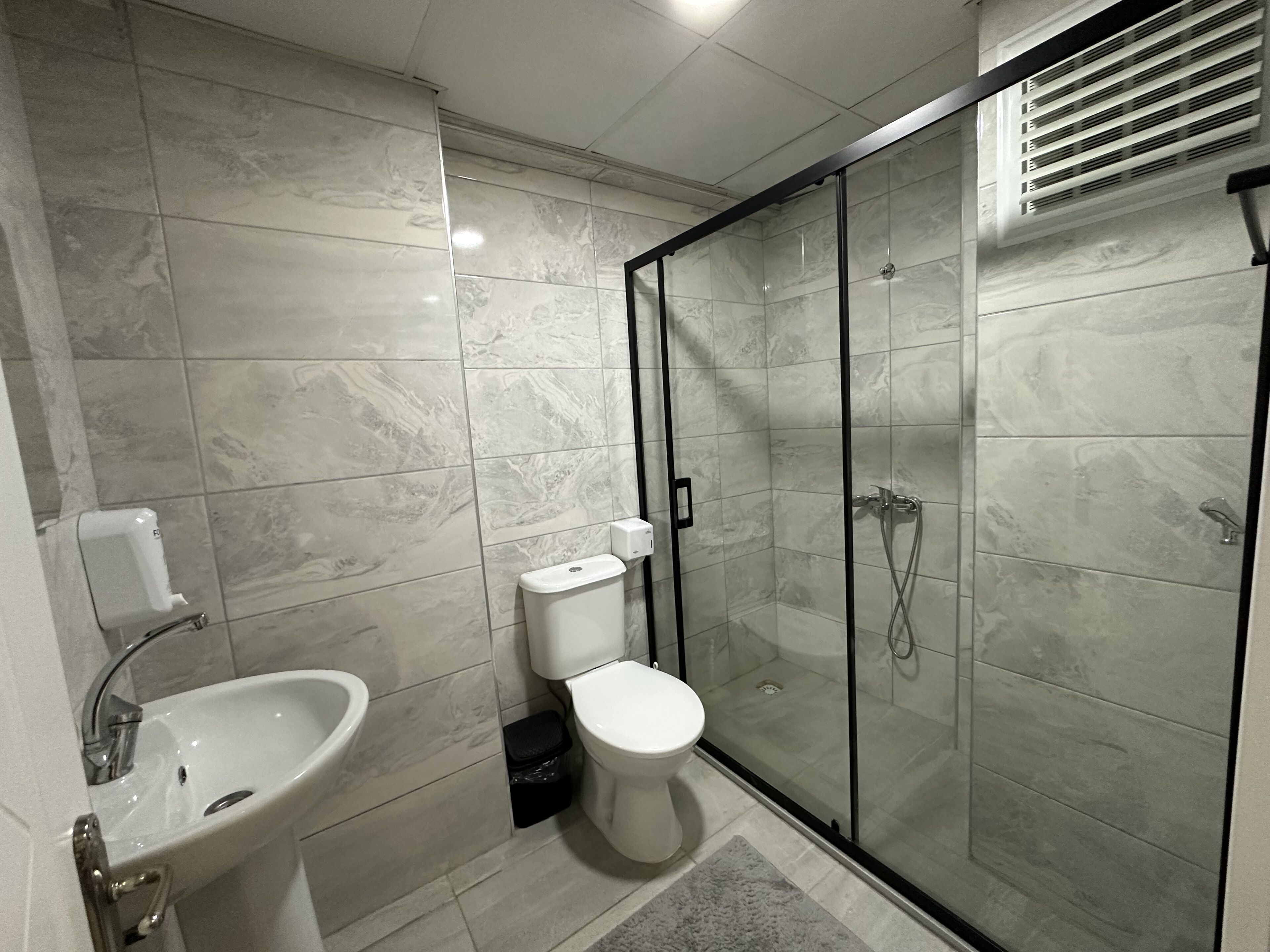 Un baño moderno con ducha envuelta en vidrio, lavamanos y retrete.