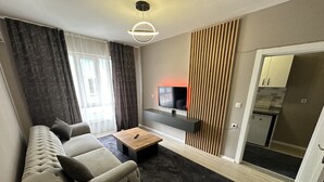 A modern living room with a sofa, a coffee table, and a TV mounted on a wooden panel wall.