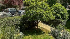 A residential area with multi-story buildings, parked cars, and lush greenery. - Athenian Coastal Urban Living (Paleo Faliro)