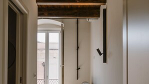 Een hal met een houten plafond, een bank en een deur naar een balkon.