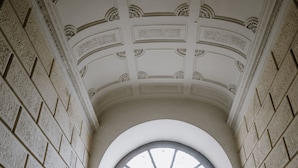Een rond dakvenster in het interieur van een gebouw, met decoratieve lijsten en bakstenen muren.
