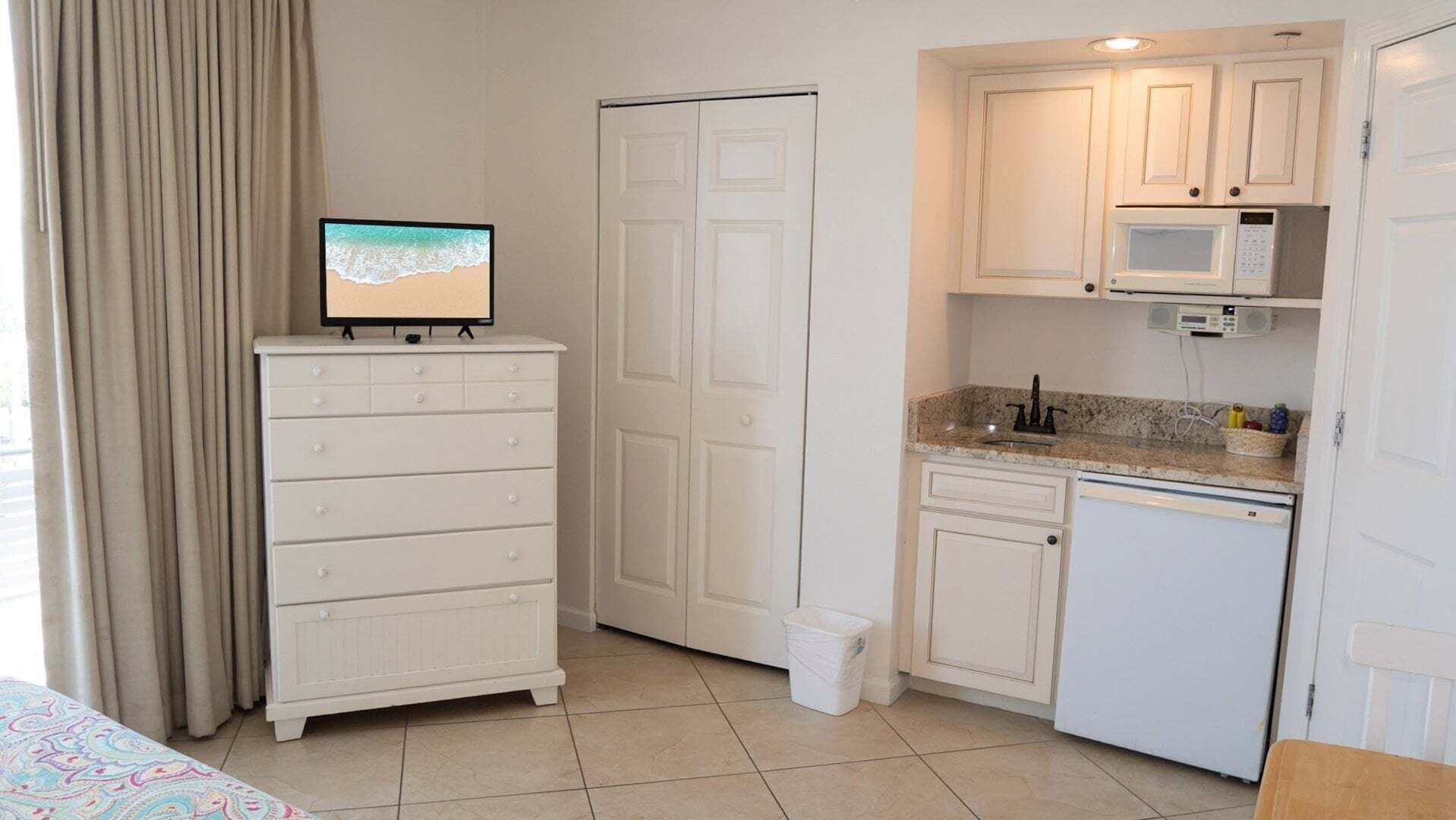 A compact kitchen with a microwave, a small refrigerator, and a cabinet.