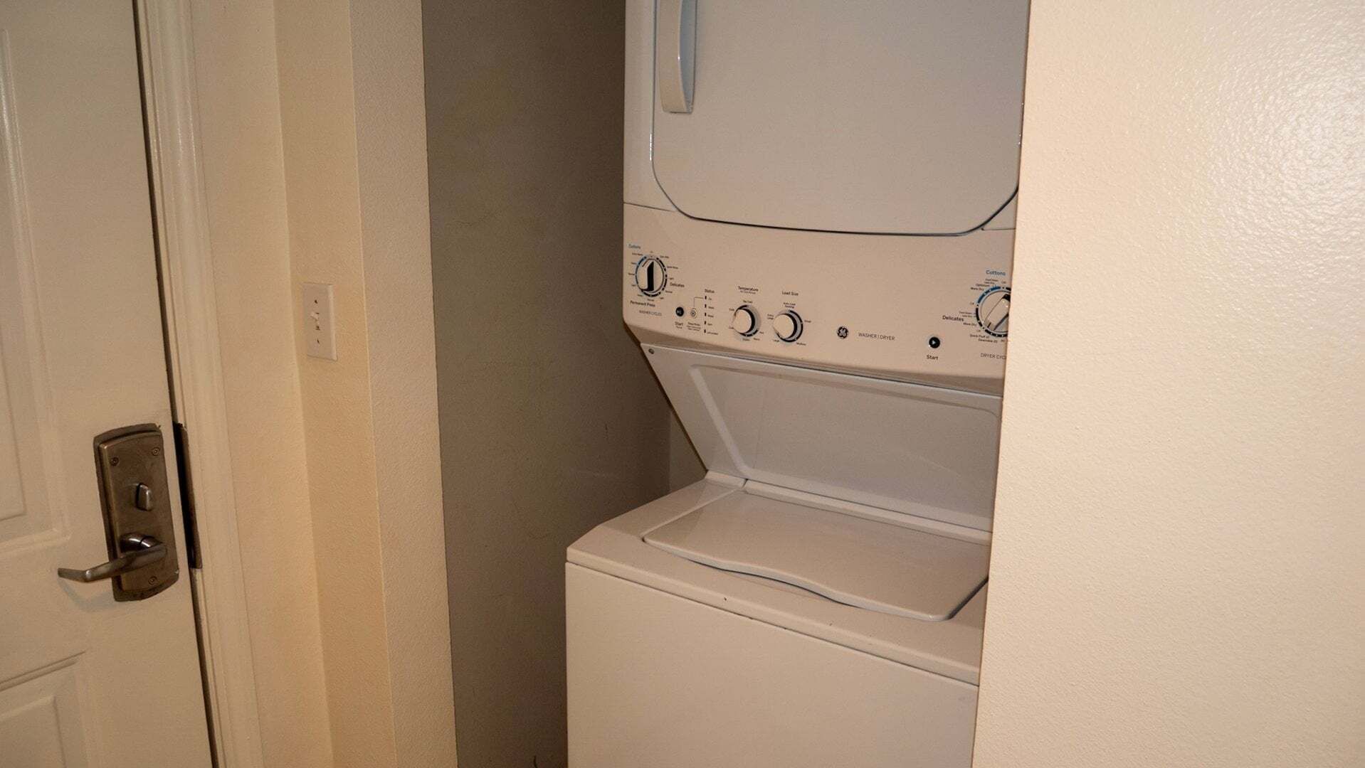 Un cuarto de lavado con lavadora y secadora, una puerta con cerradura y un interruptor de luz en la pared.