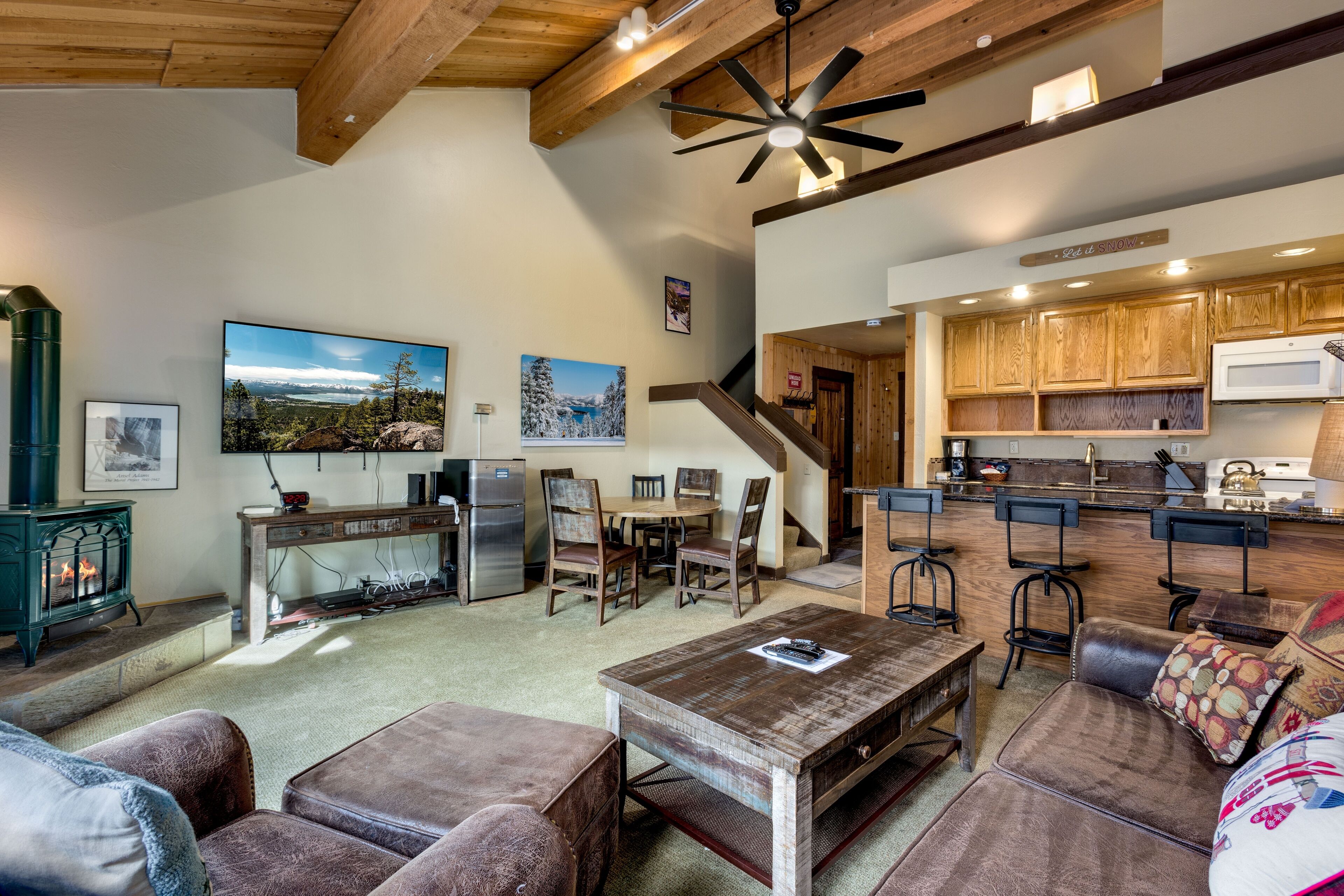 A spacious living area with a fireplace, wooden furniture, and a kitchen with wooden cabinets and a microwave.