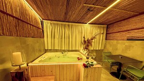 A wooden room with a bathtub, a table with chairs, and a candle on a stand. - Luff Living Adult Only (+12) (Antalya)