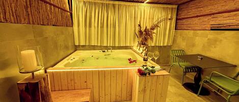 Une pièce en bois avec une baignoire, une table avec des chaises et une bougie posée sur un chandelier.