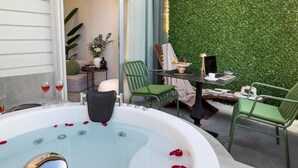 A spa area with a hot tub, green chairs, and a table with a lamp and books. - Luff Living Adult Only (+12) (Antalya)