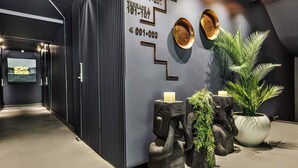 A reception area with a modern design, including a staircase, a wall-mounted information board, and a potted plant. - Luff Living Adult Only (+12) (Antalya)