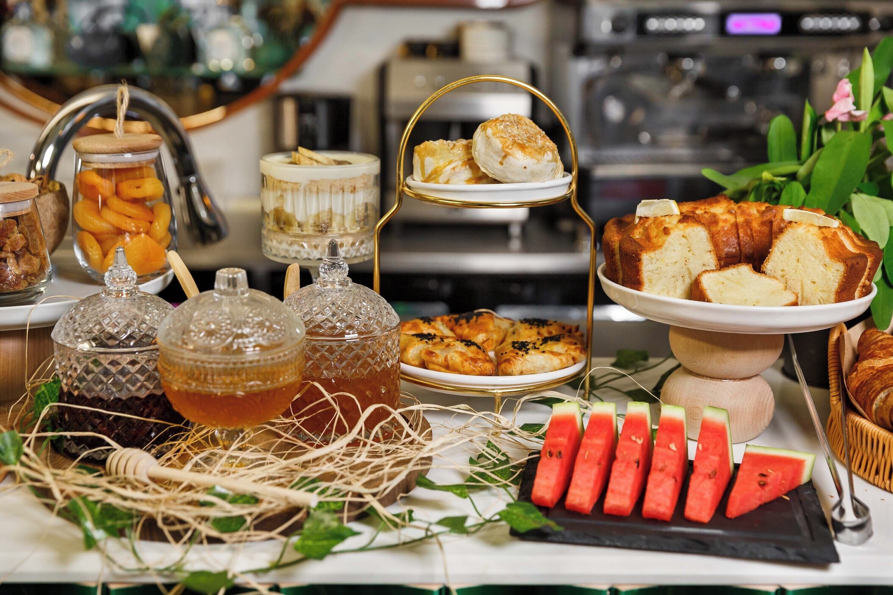 Un buffet proposant une variété de plats, notamment des pâtisseries, des sandwichs et une présentation attrayante de pastèques.